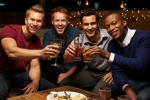 Portrait Of Male Friends Enjoying Night Out At Rooftop Bar